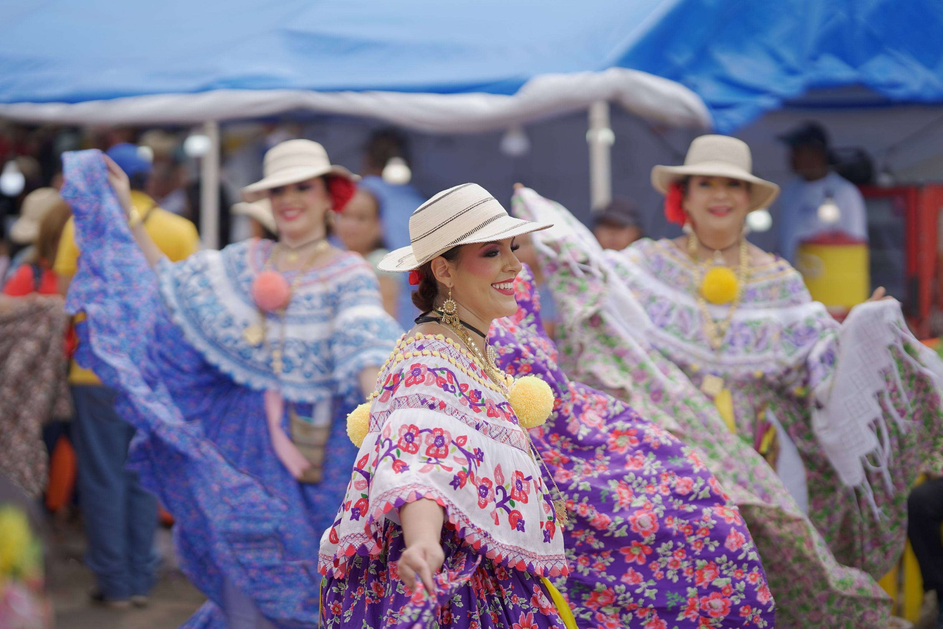 Mujeres con polleras panameñas tradicionales bailando en una celebración al aire libre