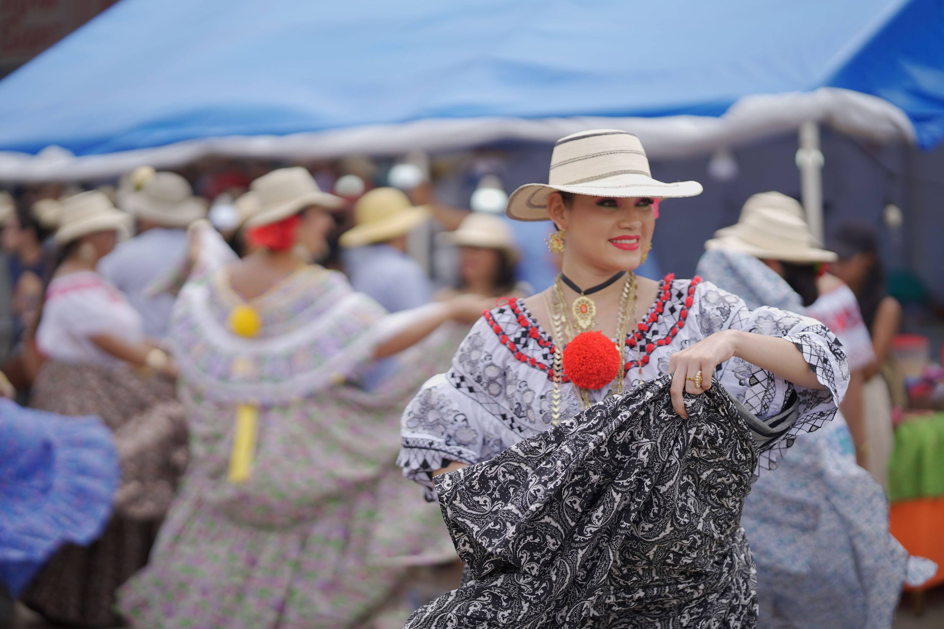 Una mujer con pollera blanca y sombrero sonriendo mientras baila